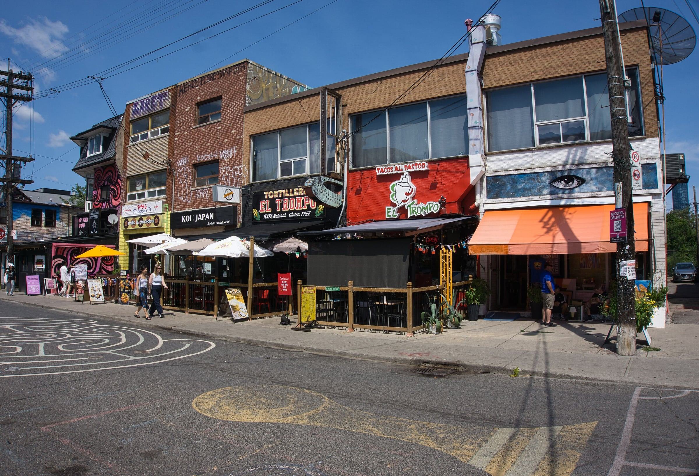 Colourful storefronts, murals and patios on a sunny Kensington Market street in Toronto