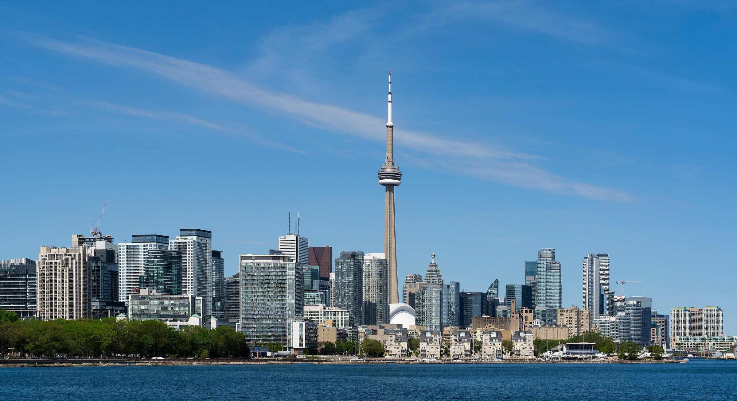 Toronto skyline with the CN Tower rising above downtown towers, seen across Lake Ontario on a clear day