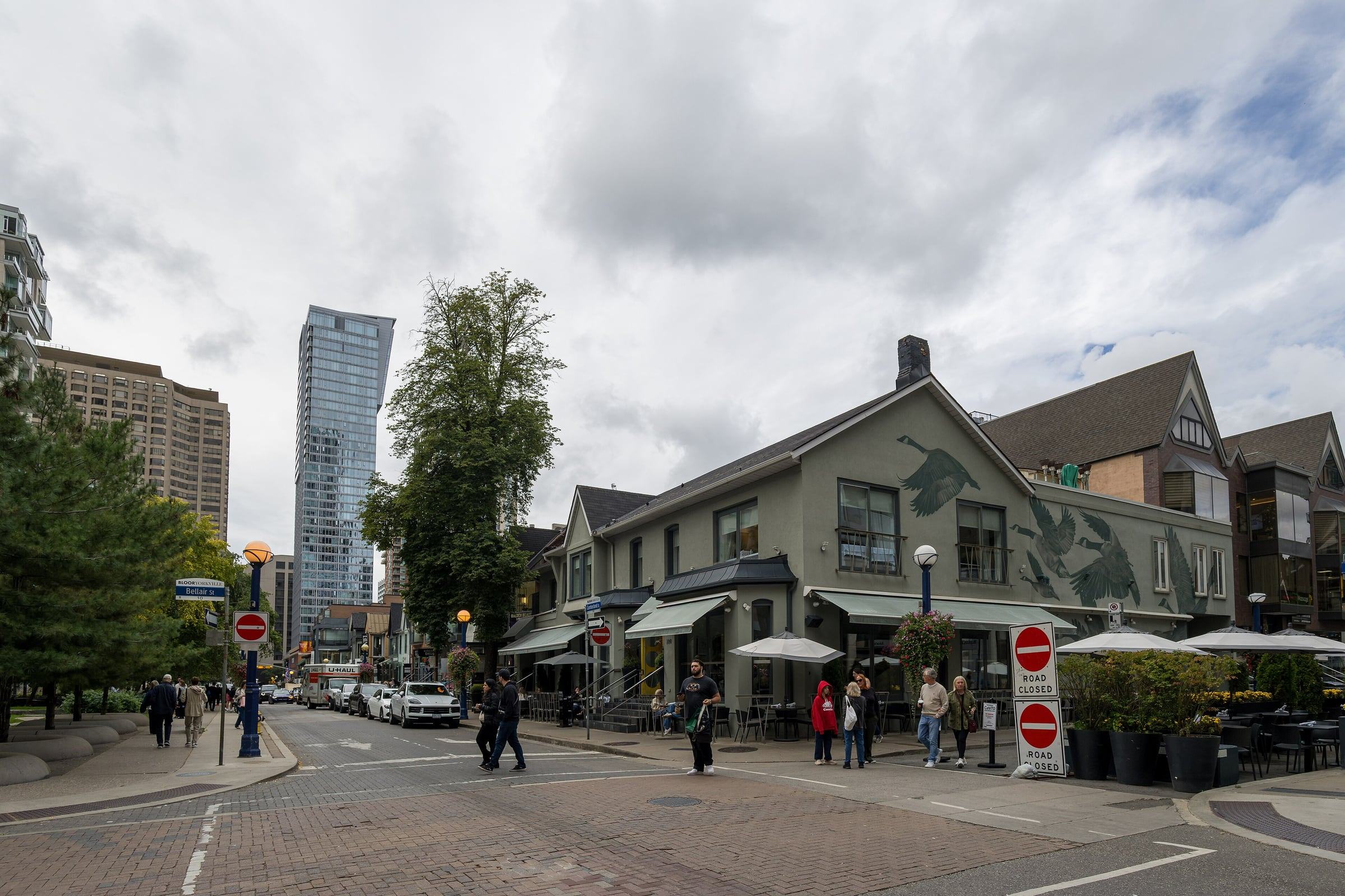 Yorkville street corner with a goose mural on a cafe building and condo towers behind
